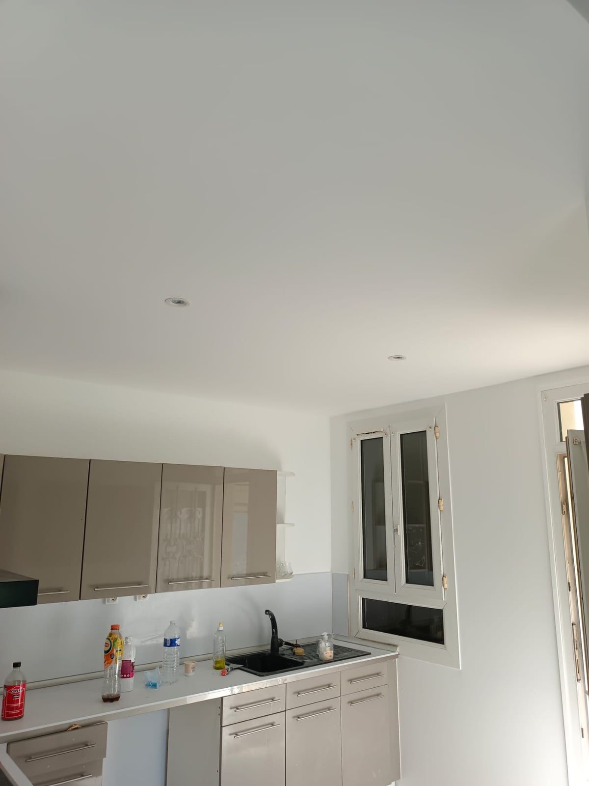 La même cuisine terminée : meubles hauts posés, plafond peint et spots encastrés allumés
