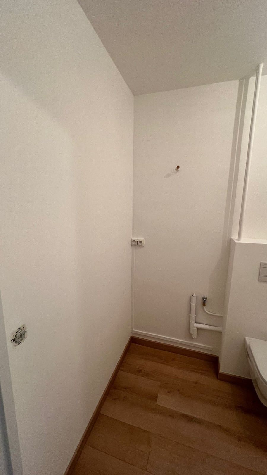 Les mêmes WC terminés : sol posé, murs peints et cuvette suspendue installée
