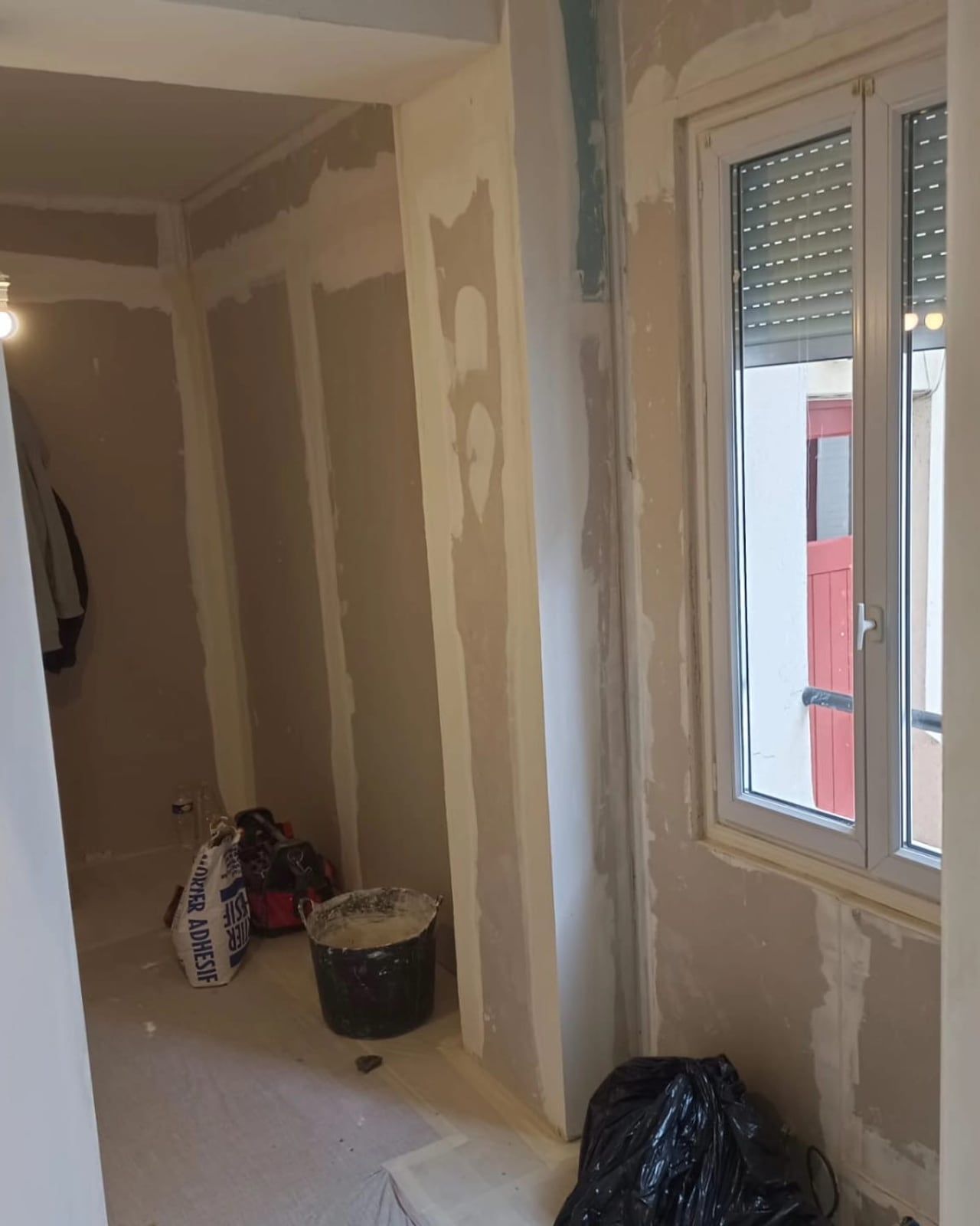 Pièce de vie avant travaux, murs nus et sol de chantier