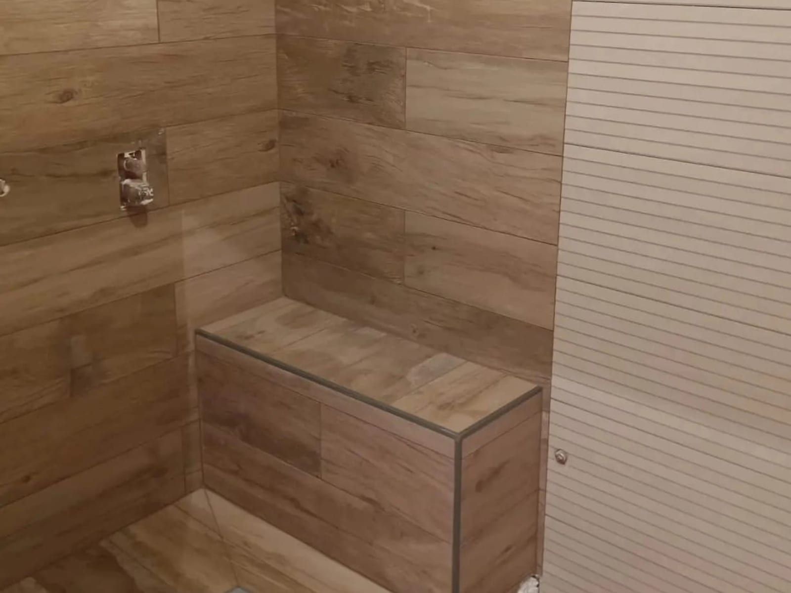 Salle de bain rénovée avec douche, paroi vitrée et faïence blanche au mur